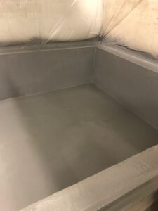 Freshly applied industrial containment coating inside a sealed enclosure.